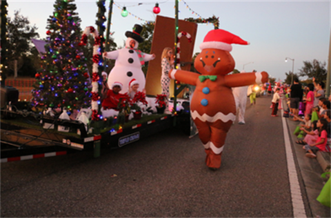 Parade unit float with inflatable Christmas characters on it and walking on the side.