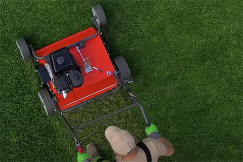 A lawn mower is pushed across a grass lawn.PNG